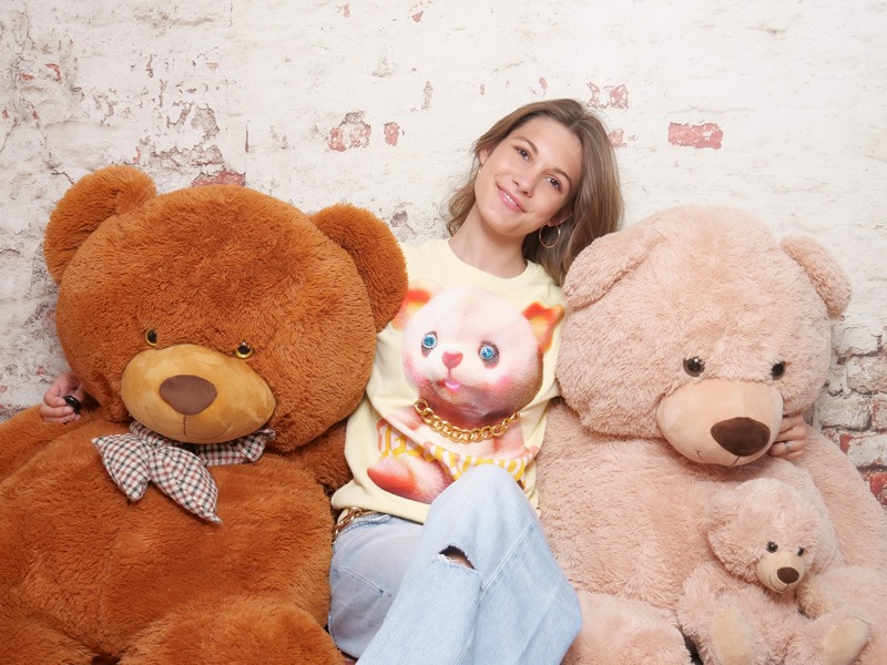 Junges Mädchen im Selfie-Studio vor einer Ziegelwand mit grossen Teddybären
