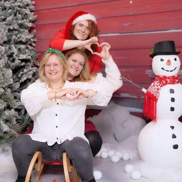 Drei Frauen auf einem Rodelschlitten im Selfie Studio bei Weihnachts Fotoshooting